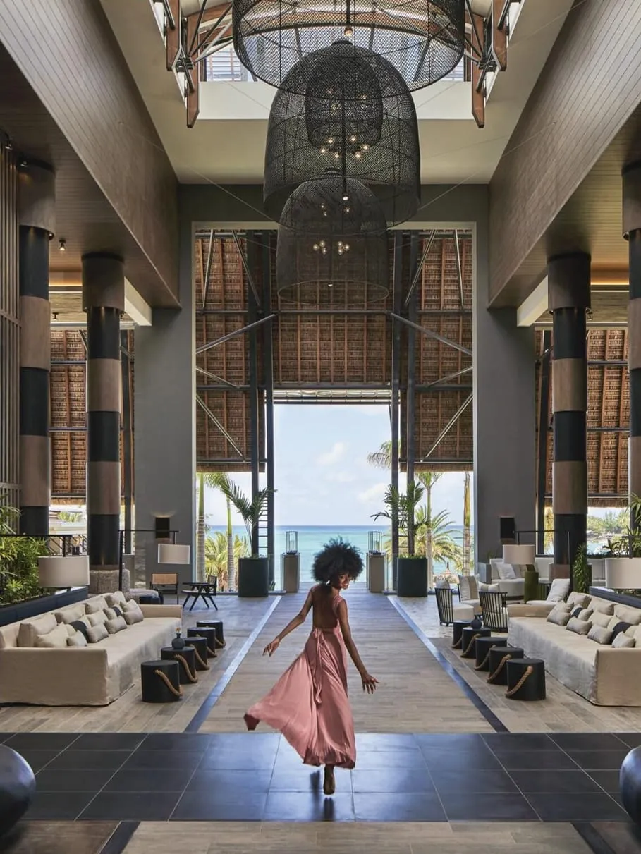 The double height lobby, a woman crossing the stone floor towards the daylight at the far end