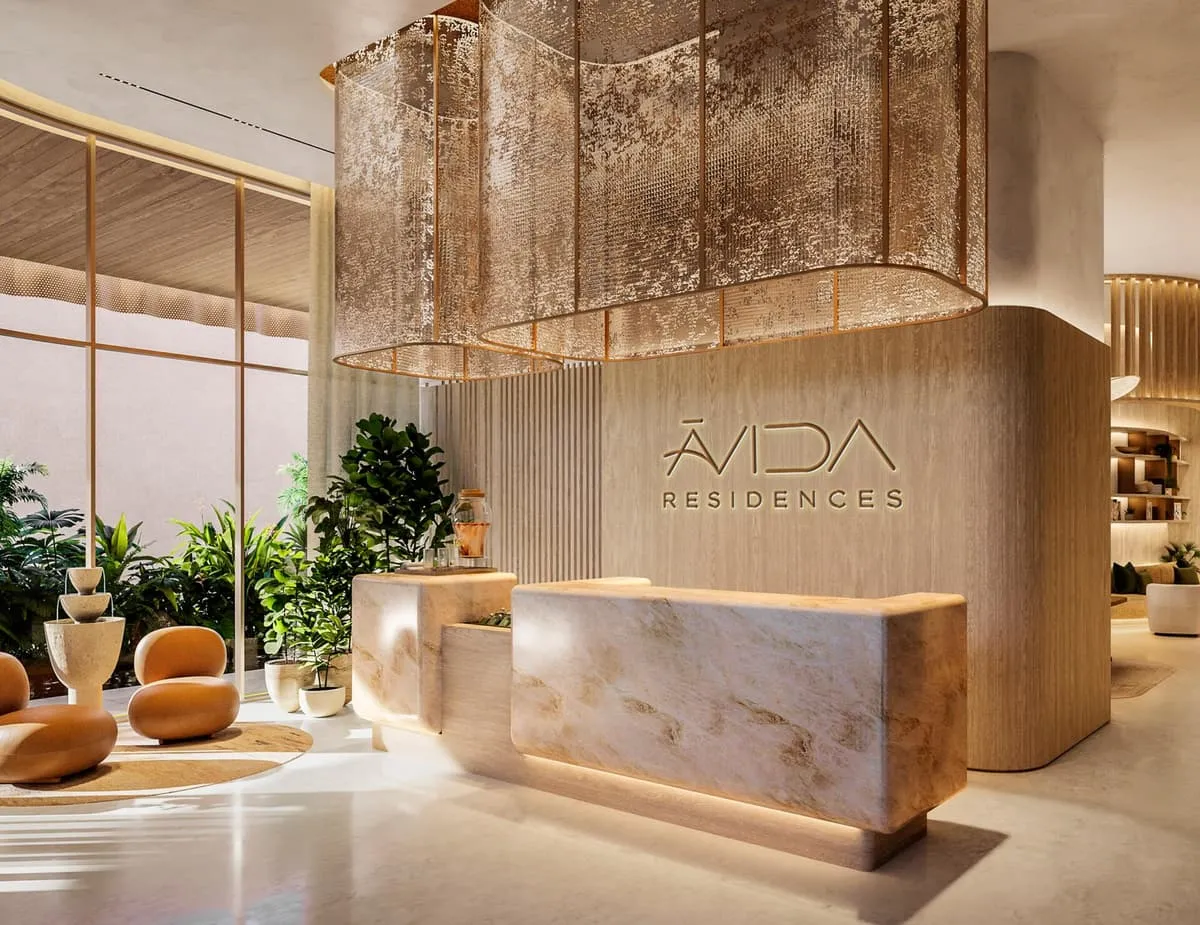 The lobby, a stone reception desk in front of a textured gold wall carrying the Avida Residences name