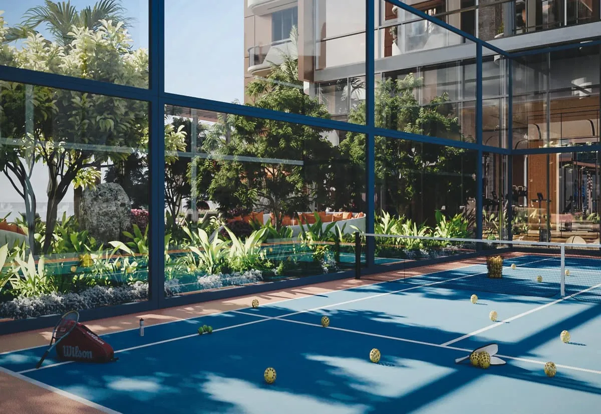 The padel court, a blue surface behind glass walls with planting around it and the tower above