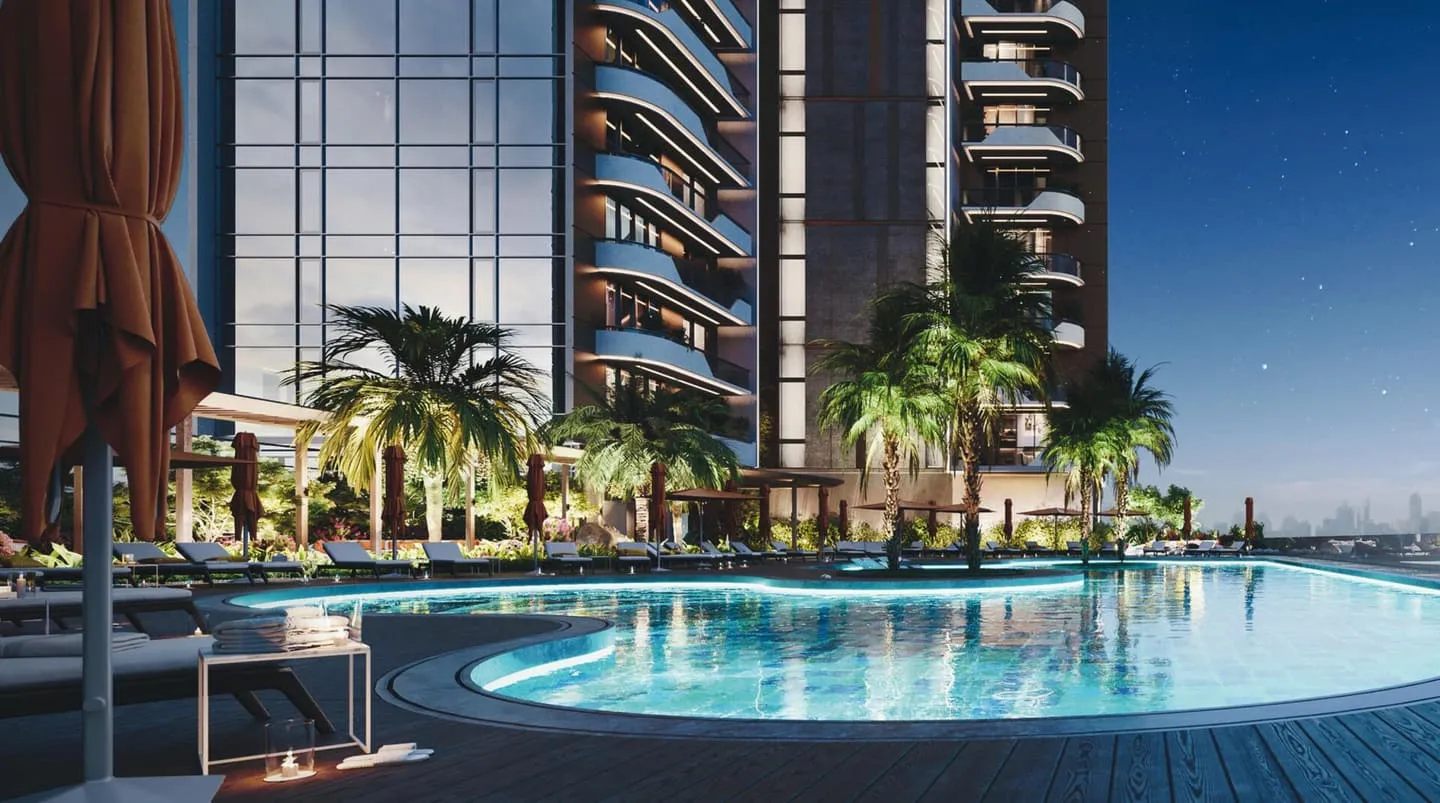 The main pool at dusk, palms lit from below and the towers standing behind the water