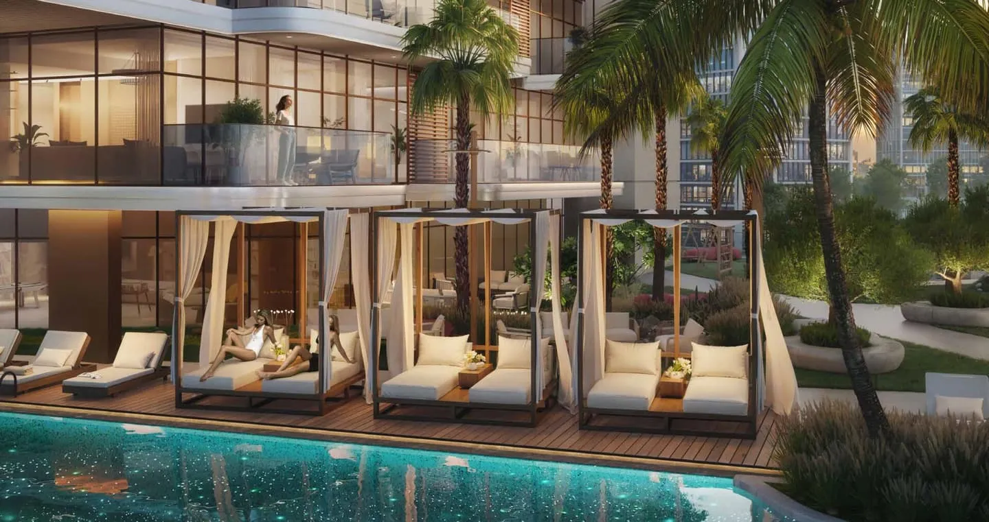The pool deck, shaded cabanas and sun loungers along the water with palms and the building behind