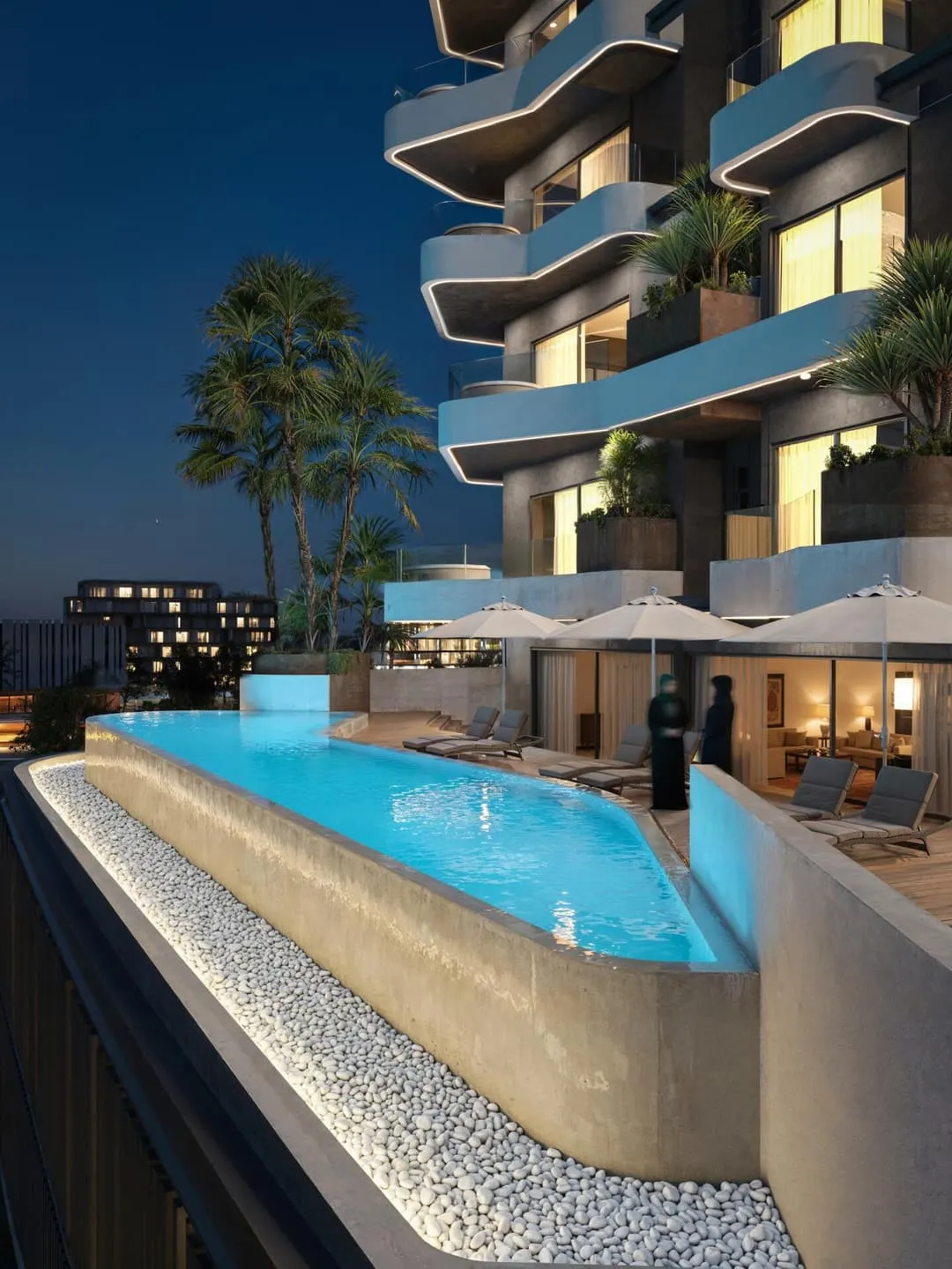 The pool deck at dusk, lit blue against the tower's balconies and the surrounding palms