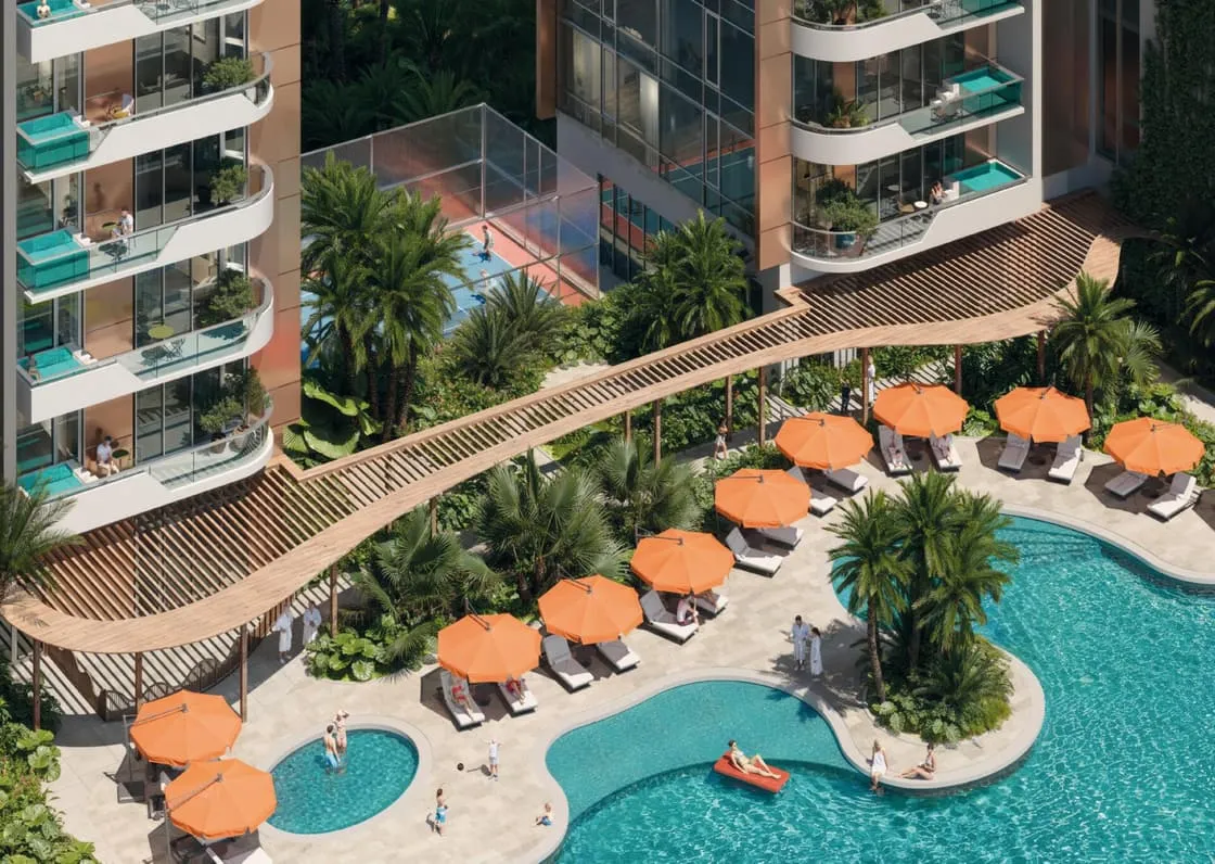 The pool deck from a balcony above, orange parasols and loungers along a curved timber edge
