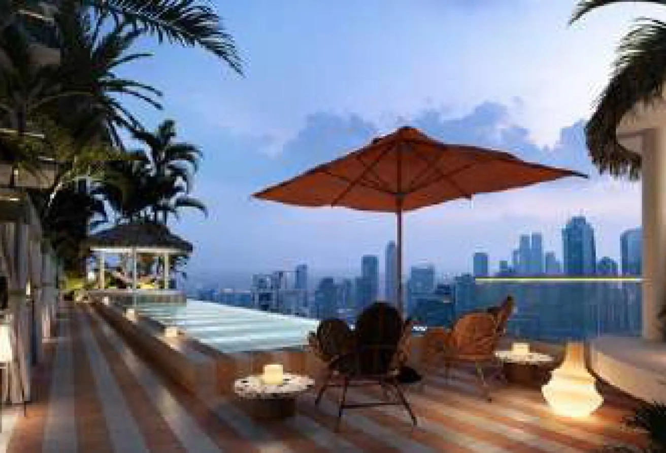 Render of a pool deck with a red parasol and wicker armchairs, facing the skyline at dusk