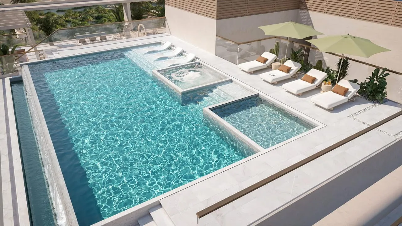An aerial view of a second rooftop pool with twin jacuzzis and shaded loungers around it