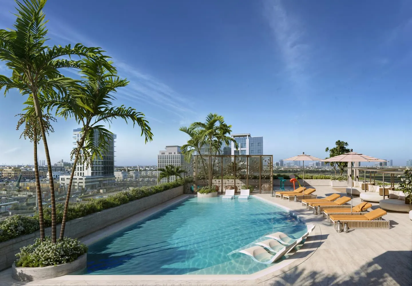 The pool in daylight, palms along the deck and loungers set out on the paving under a clear sky