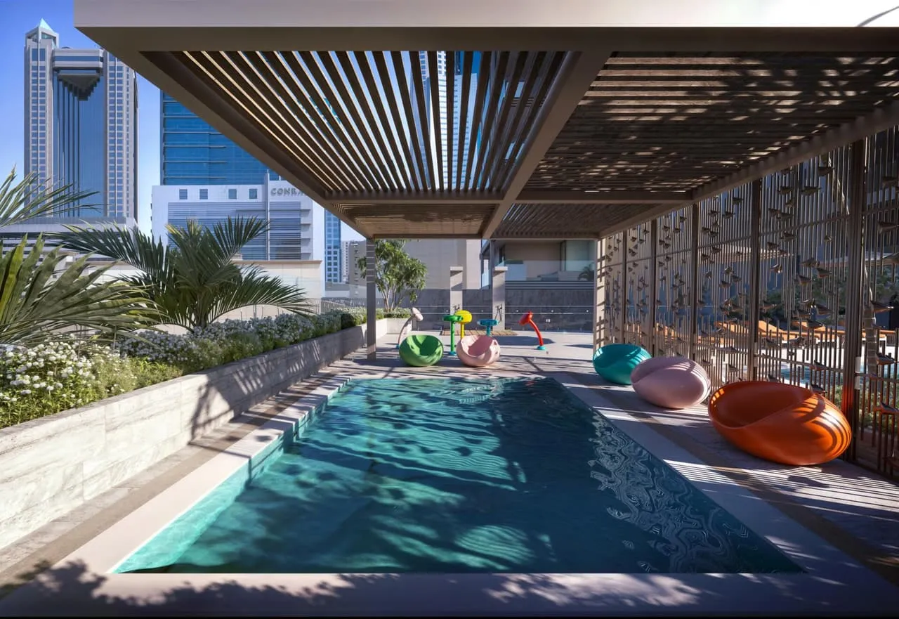 The pool under a slatted pergola, low loungers on the deck and the towers of the district behind the planting