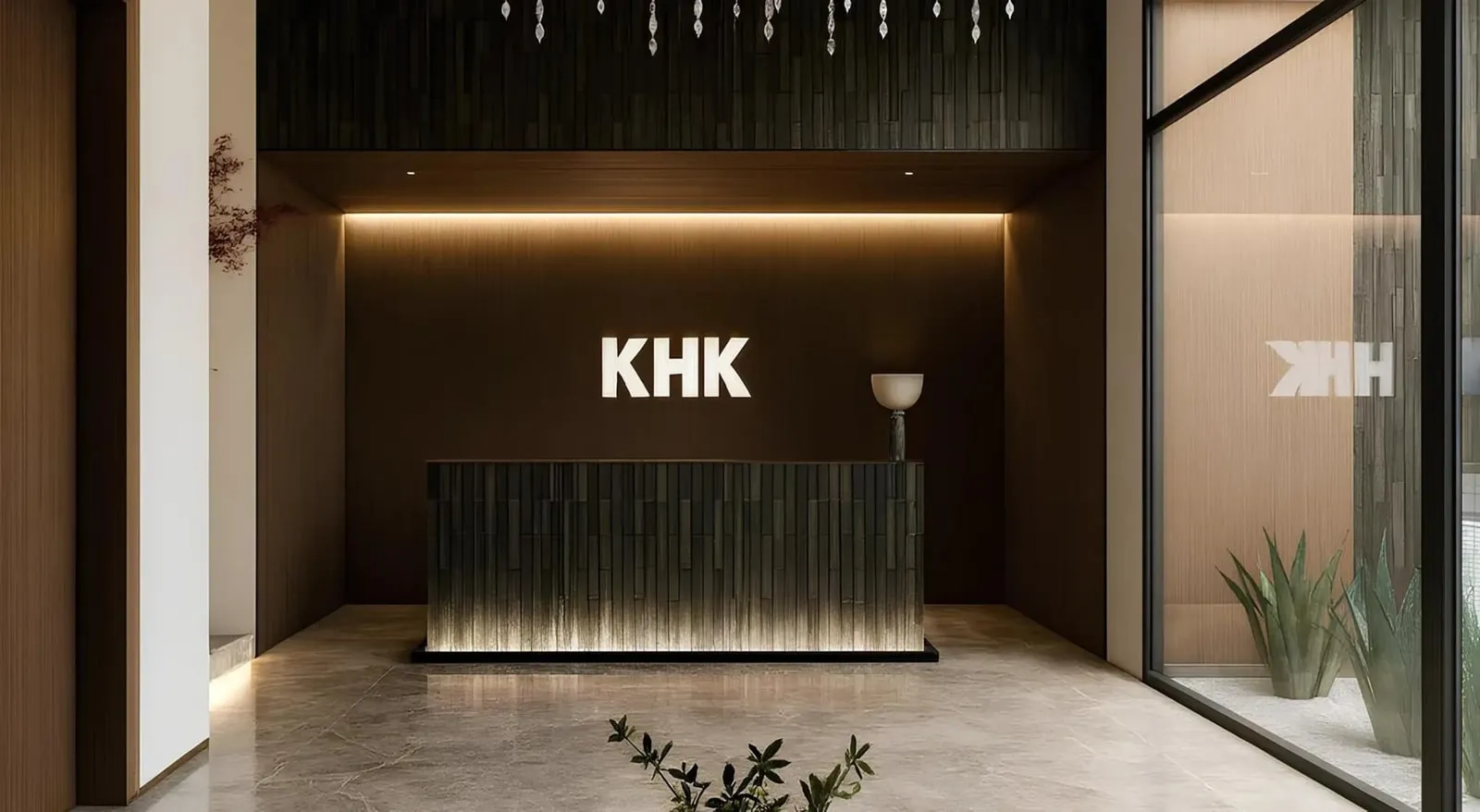 The reception desk, the KHK lettering backlit on a dark ribbed wall with a table lamp at one end