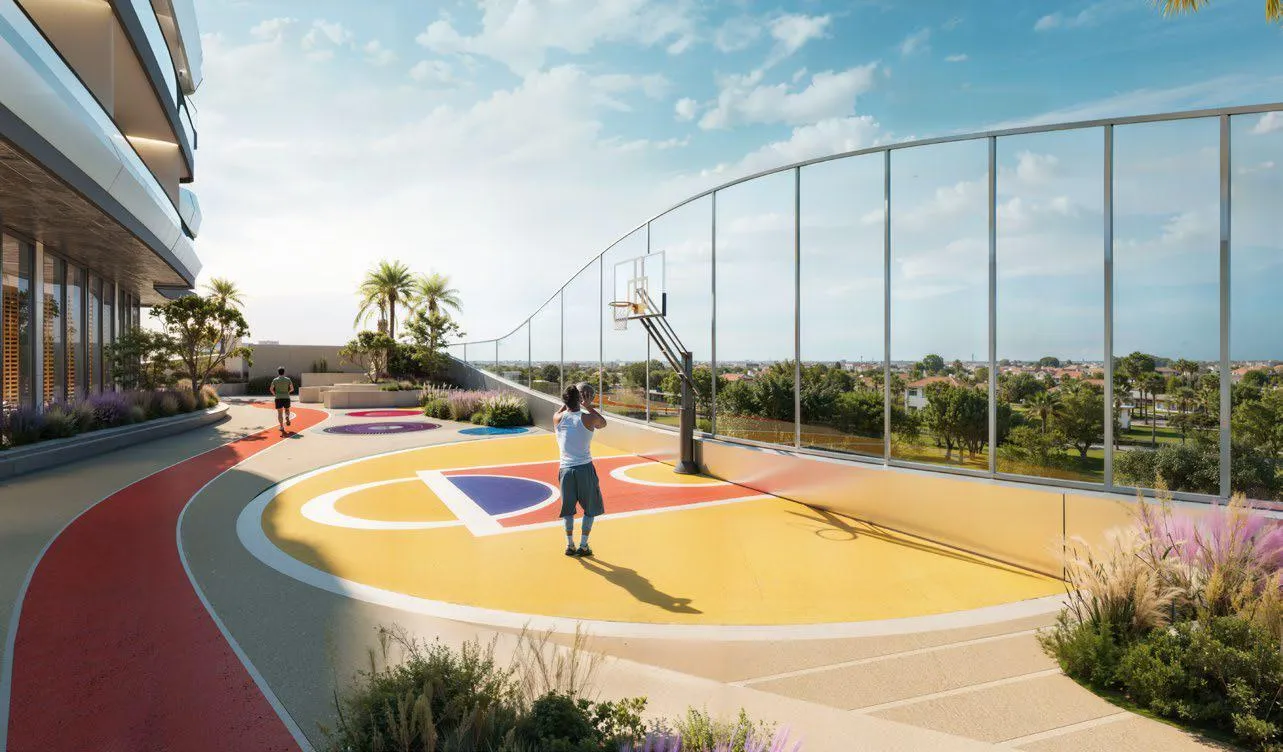 A rooftop court, a basketball hoop over red surfacing inside high perimeter netting with the district beyond