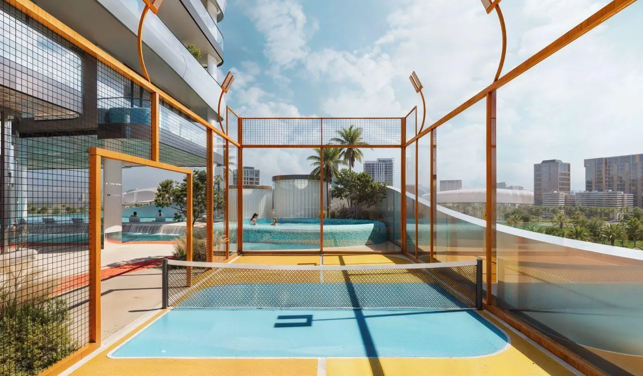 Two fenced rooftop courts, blue playing surfaces inside orange run-offs under an orange frame structure