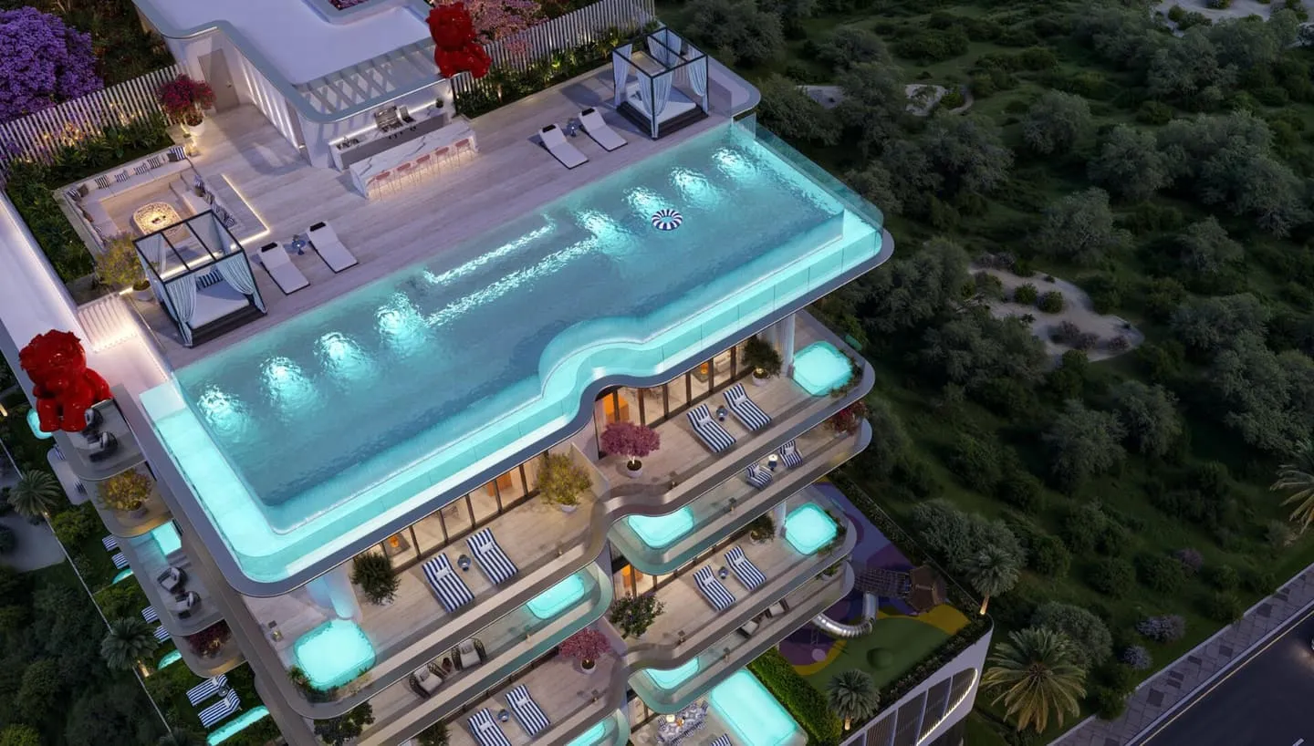 An aerial view of the rooftop deck at dusk, the lit pool and cabanas beside the red bear sculpture