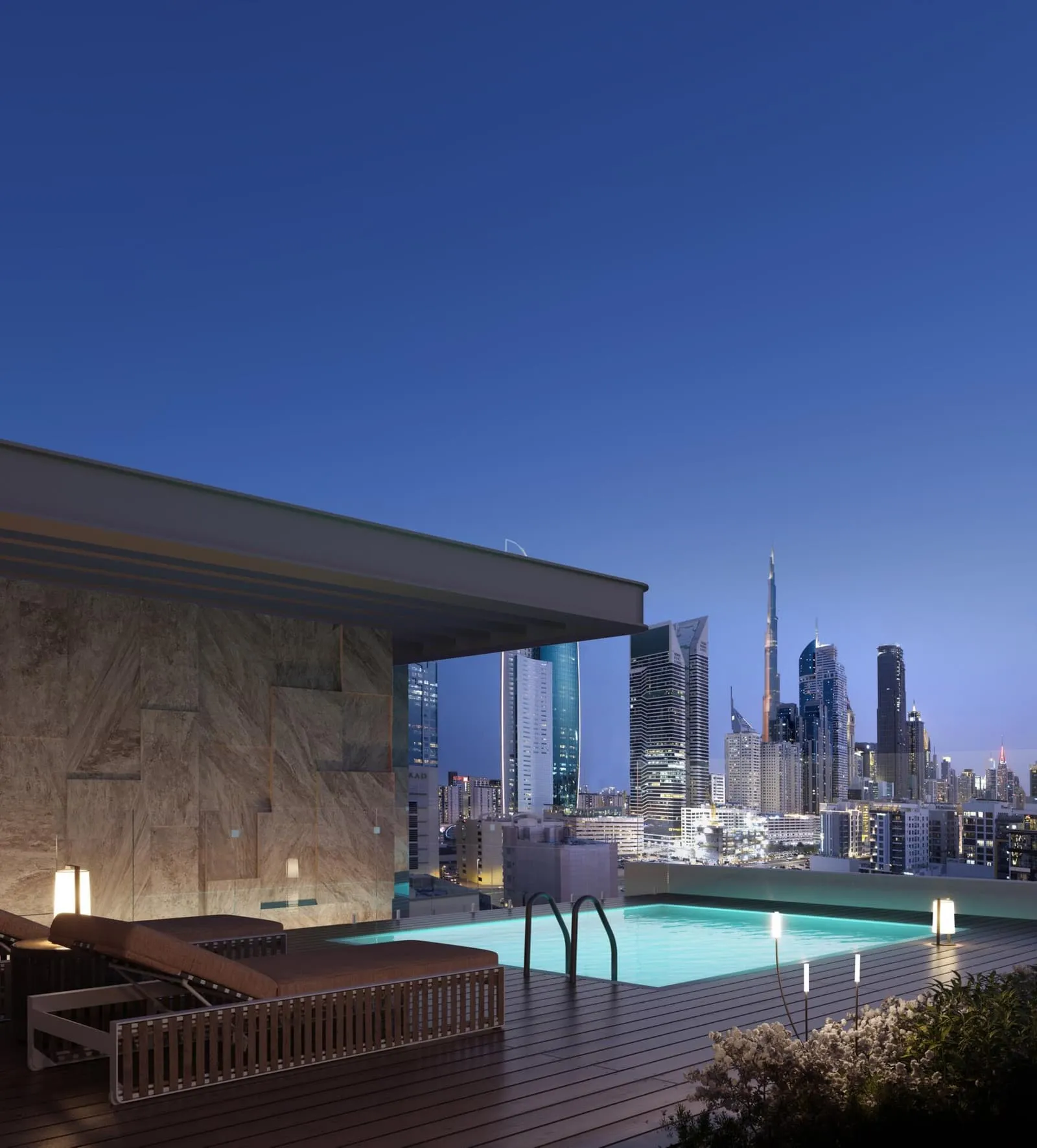 The rooftop pool after dark, the water lit from within and Burj Khalifa on the skyline past the deck