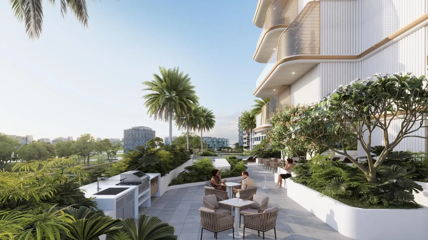 A shaded terrace with small dining tables and chairs, planting between them and open water beyond