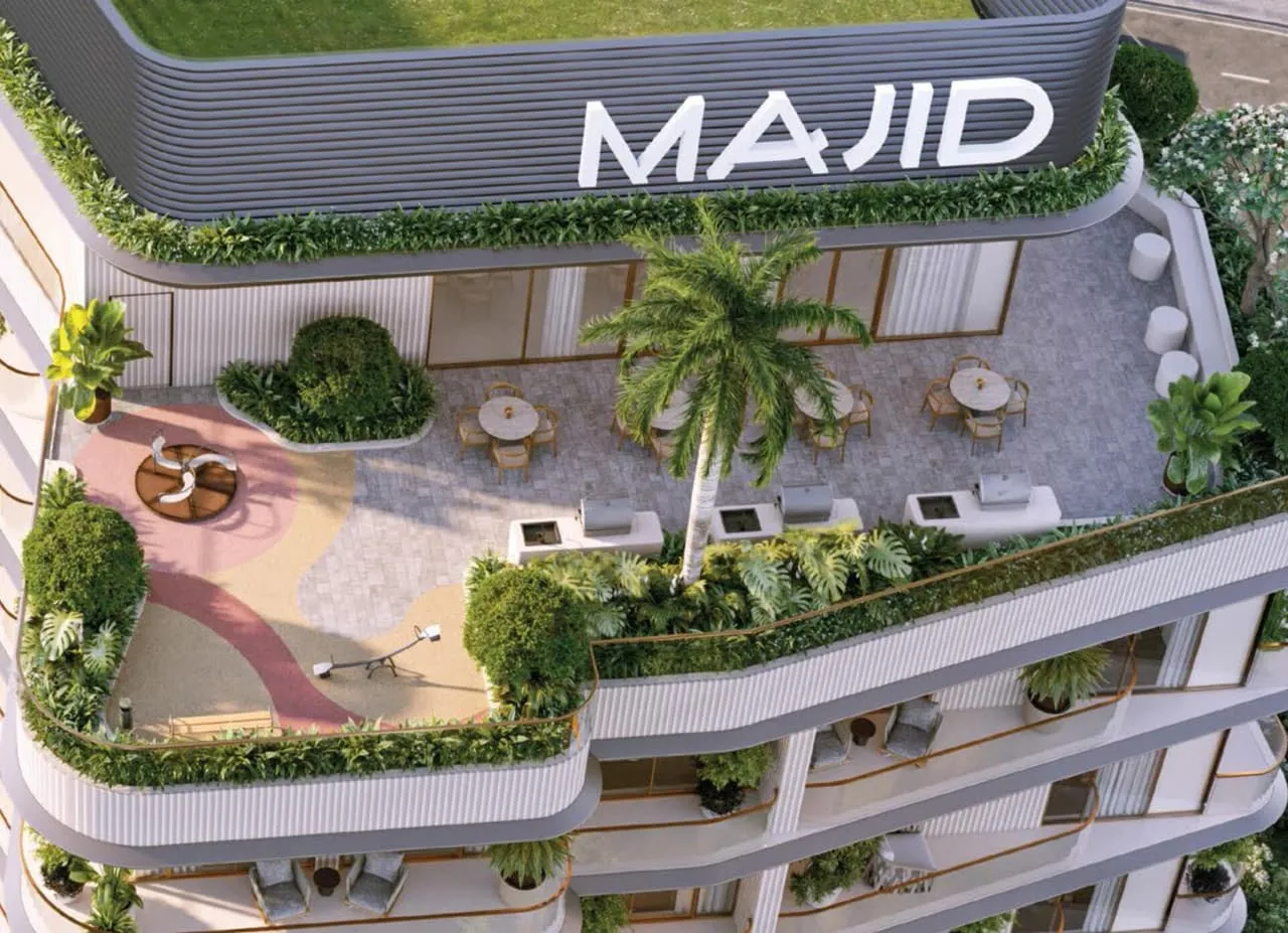 The roof terrace from above, tables under a palm and planting along the edge of the curved balconies below