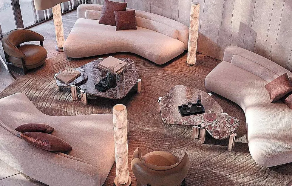 A curved blush sofa seen from above, a low table with glass objects on a patterned timber floor