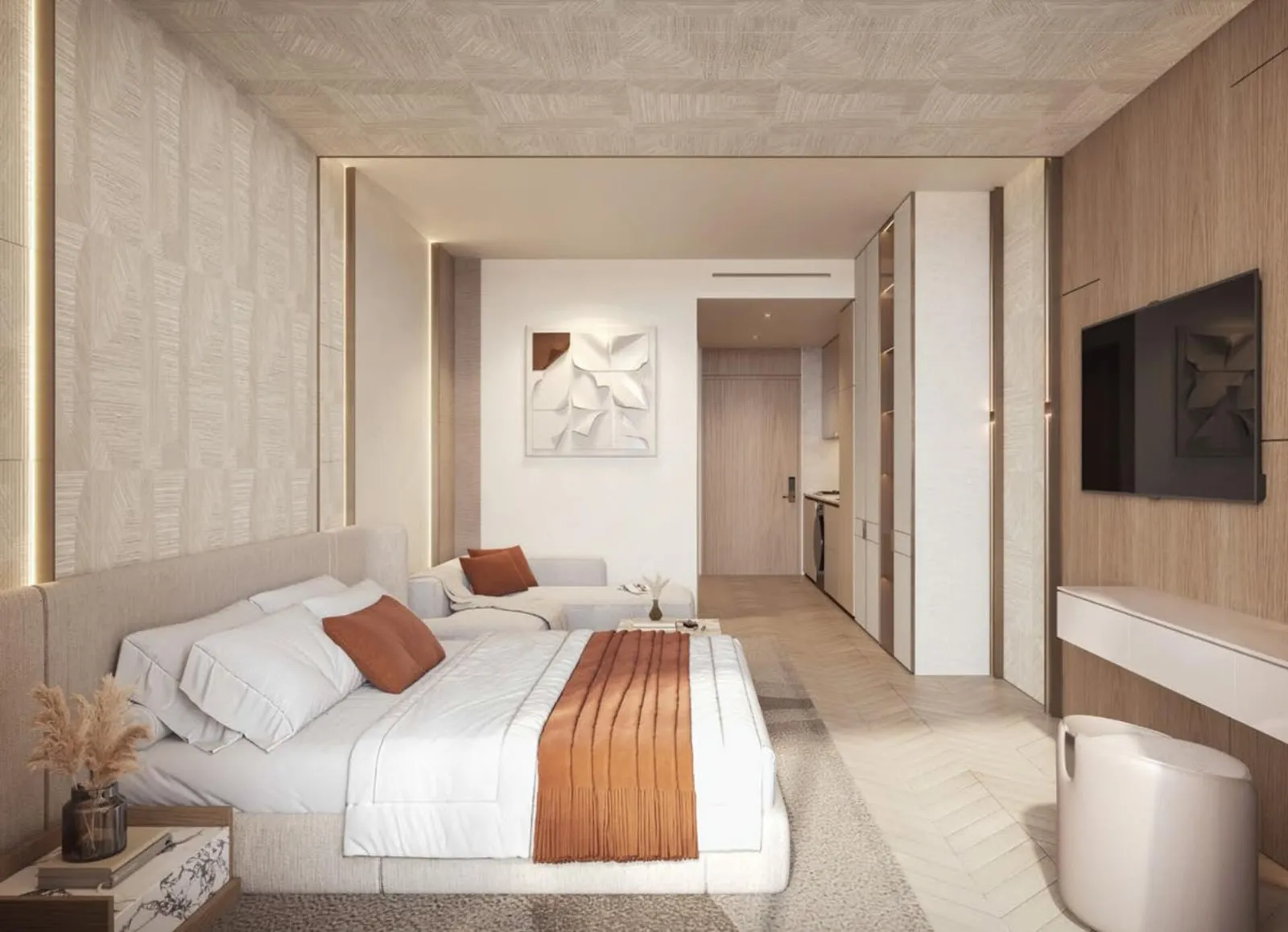 A single room with a bed, a sofa at its foot, a wall-mounted screen on timber panelling and a kitchen beyond the hallway