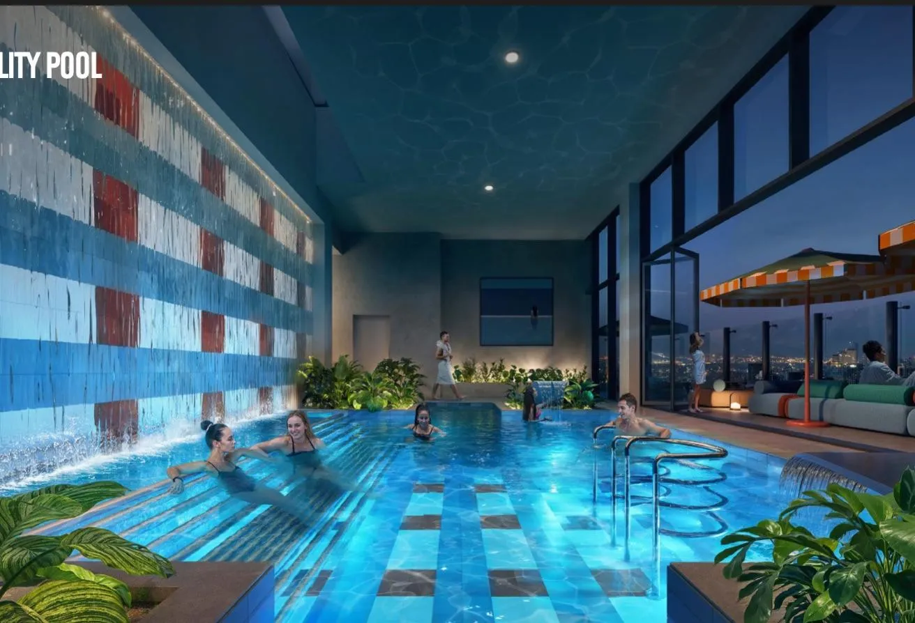 Render of an indoor pool lit blue, with a patterned tile wall and a view out to palm trees