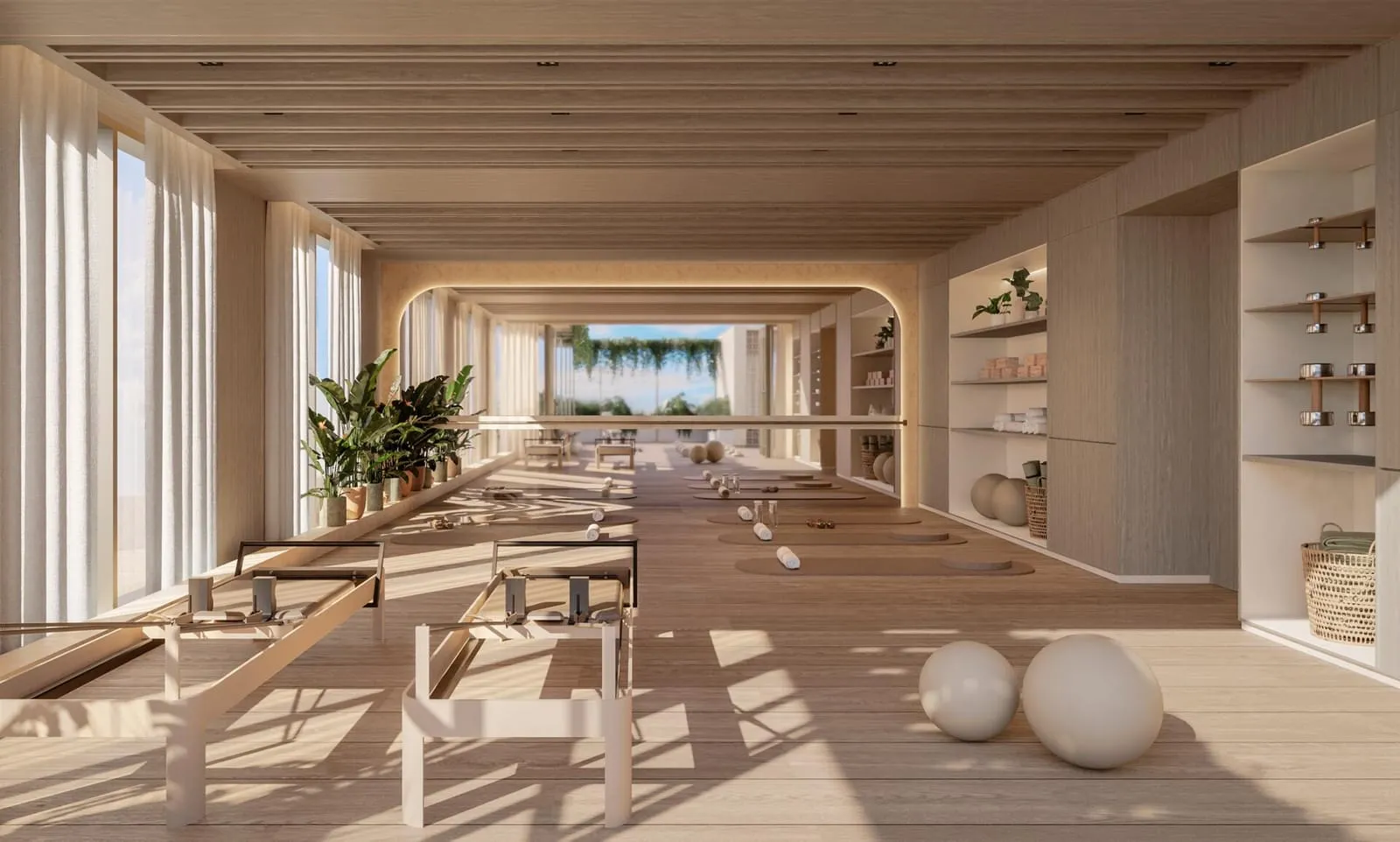 A long, sunlit wellness room lined with timber loungers, shelving and exercise balls