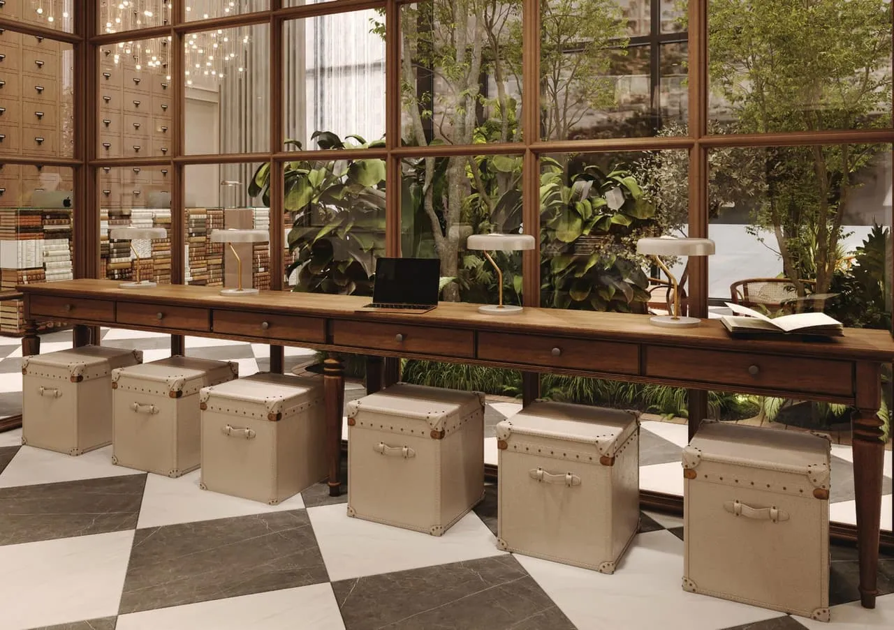A long timber desk with trunk stools along it, facing the planted courtyard through the glass